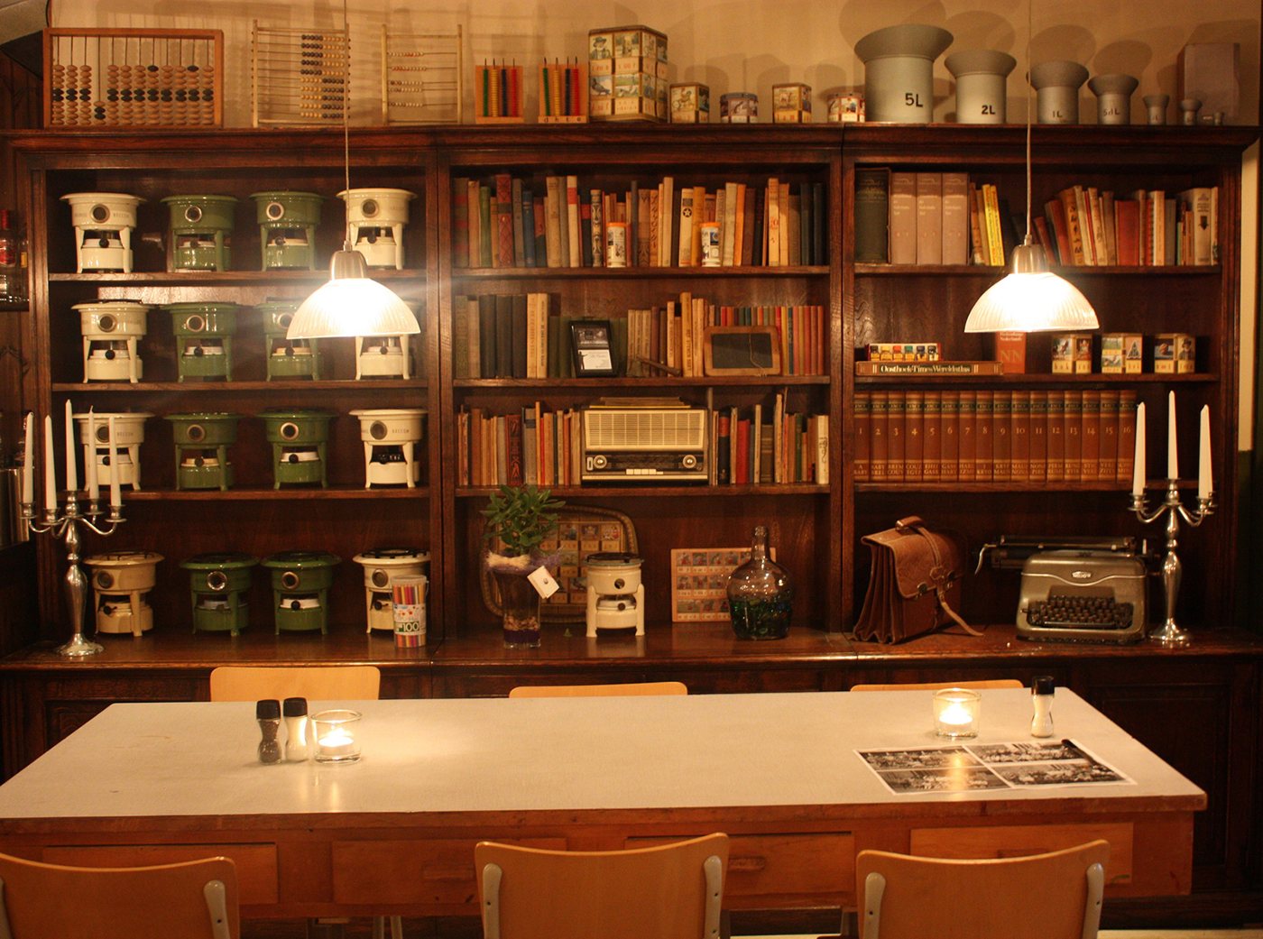 Wandkast met oude fondue-rechauds, schoolboeken, telramen en een leren schooltas